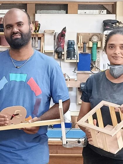 Another pair of makers with their creations. One made a snail-shaped clock, and the other built a magazine or book holder.