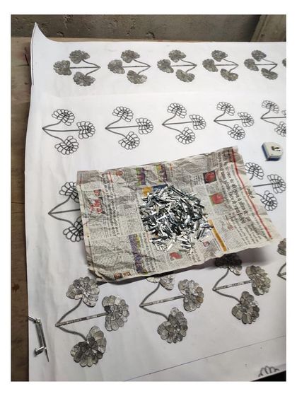 A work-in-progress photo showing the tools of the Thikri trade: a template, adhesive, and a pile of delicate, mirrored glass pieces.