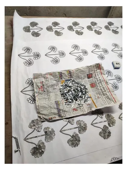 A work-in-progress photo showing the tools of the Thikri trade: a template, adhesive, and a pile of delicate, mirrored glass pieces.