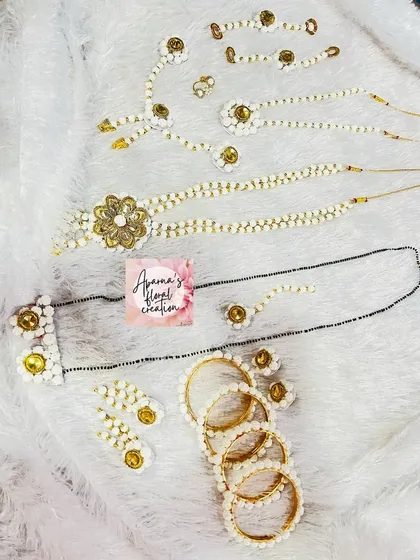 A full set of halwa jewellery laid out, including a mangalsutra, bangles, necklaces, and earrings, all made from tiny sugar beads.