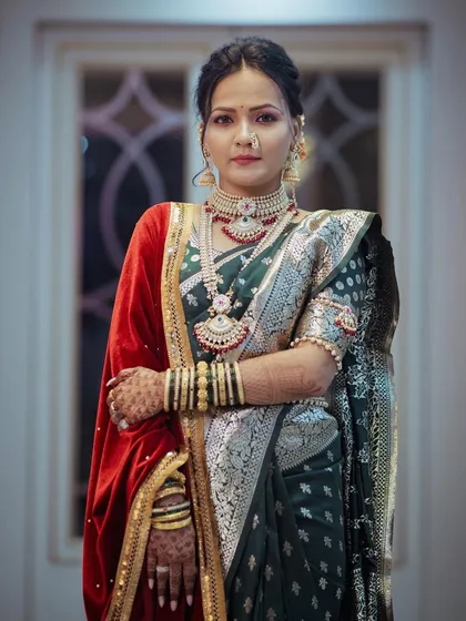 A stunning solo portrait of the bride in her royal wedding attire. The combination of a green paithani saree and a red velvet shawl creates a regal and unique look.