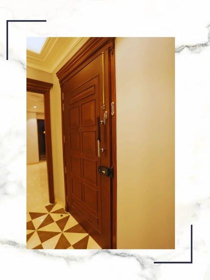 A close-up of a solid wood main door, featuring a classic paneled design and high-security locks. The craftsmanship is evident in the precise joinery and smooth finish.