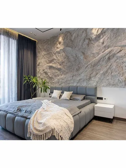 A full view of the bed and the dramatic rock wall, showcasing the contrast between the rough stone and the soft, comfortable bedding.