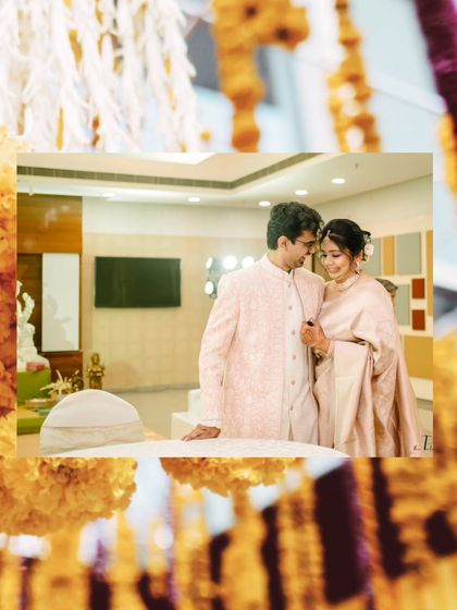 A creatively framed shot of the couple, seen through hanging marigold decorations, adding a touch of tradition to a modern portrait.
