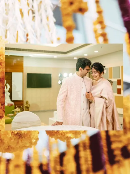 A creatively framed shot of the couple, seen through hanging marigold decorations, adding a touch of tradition to a modern portrait.