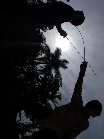 An action shot showing the dynamic movement of fencing, with one fencer lunging forward as the other prepares to defend.