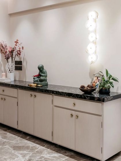 This entryway console is both practical and beautiful. The fluted cabinet doors, black marble top, and minimalist decor create a welcoming first impression, with a small Buddha statue adding a touch of serenity.