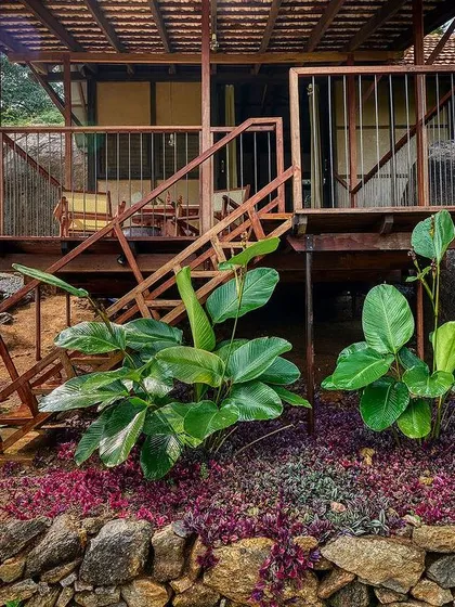 The entrance to the cottage deck, with wooden stairs leading up from a garden path. The landscaping uses local stone and native plants.
