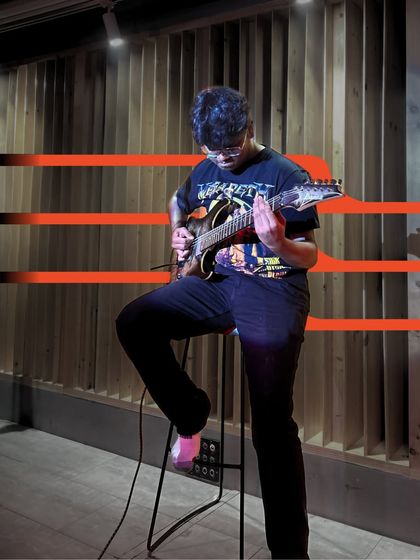 A guitarist performing at our May Intramural, set against our signature wooden sound panels. The atmosphere is just as important as the music.