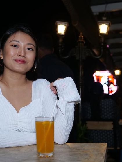 A guest enjoying a drink on the rooftop. The warm lighting from the lampposts and the night air make for a classic and pleasant pub experience.