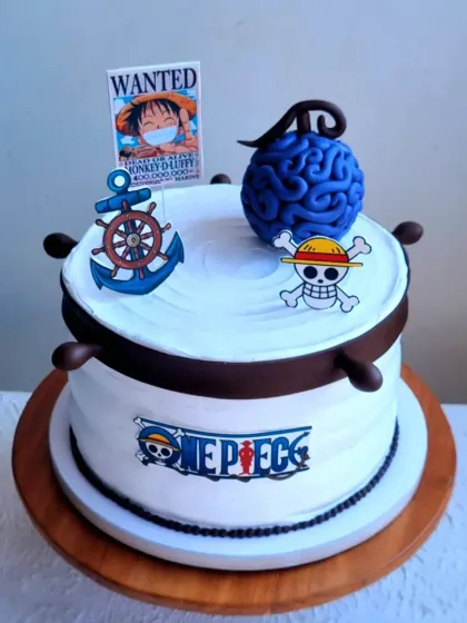 Another angle of the One Piece anime cake, showing the details of the ship's wheel and Devil Fruit topper.