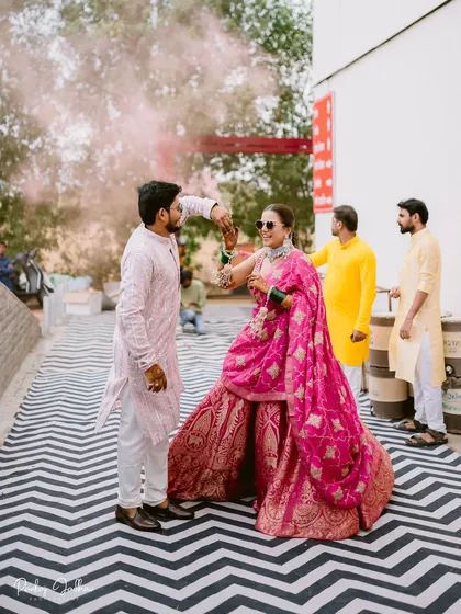 Dancing their way into the celebration, Pratibha and Paresh are surrounded by pink smoke and happy guests.