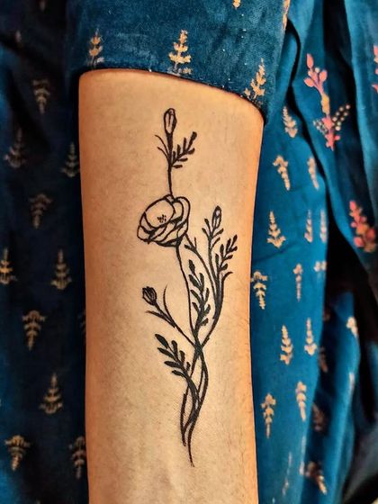 A simple and elegant black ink style floral temporary tattoo on the arm.