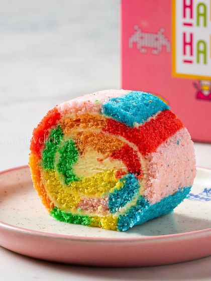 A colorful rainbow Swiss roll, sliced to reveal its vibrant layers, making for a playful and eye-catching dessert photograph.
