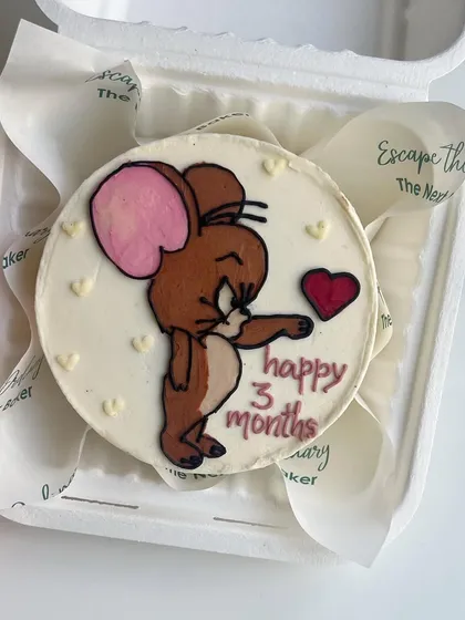 A sweet anniversary mini cake featuring Jerry the mouse holding a heart. These custom doodles are perfect for celebrating relationship milestones.