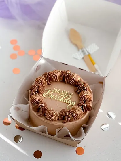 It's all in the details. This mini birthday cake features intricate chocolate piping and delicate pearl sprinkles, showing how even a small cake can be a beautiful centerpiece for your celebration.