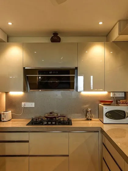 This C-shaped kitchen in a warm beige acrylic finish is perfect for those who love a neutral, calming aesthetic. The open counter creates a connection with the adjoining dining space.