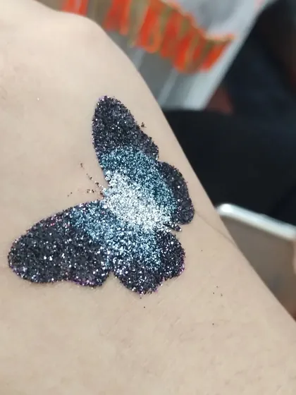 A simple butterfly tattoo with a beautiful black and silver glitter blend. It looks like a starry night sky on its wings.