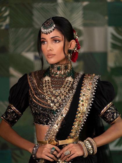 A regal and powerful look. The makeup is inspired by royalty, with a focus on defined eyes and a strong brow, paired with a stunning black and gold lehenga.