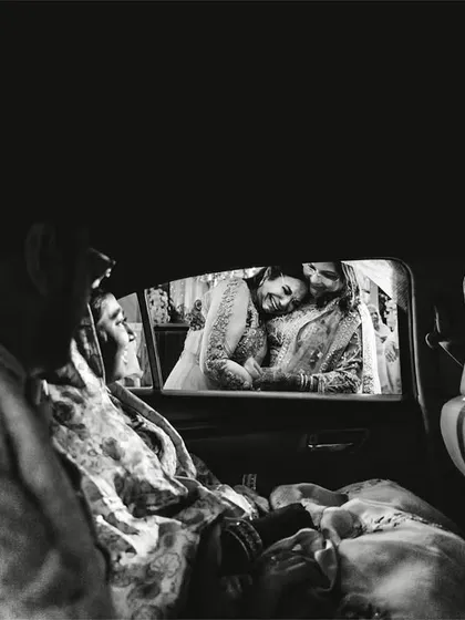 An emotional goodbye. This black and white shot from inside the car captures the poignant moment of the vidaai, a daughter's farewell to her family.