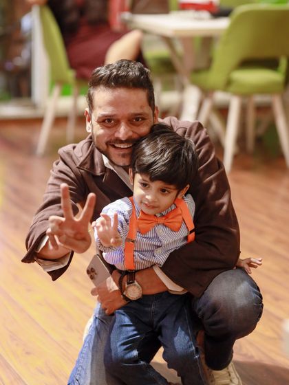 A father and son, dressed in Blippi's signature orange and blue, share a happy moment at the party.