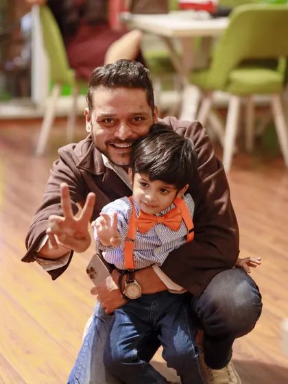 A father and son, dressed in Blippi's signature orange and blue, share a happy moment at the party.