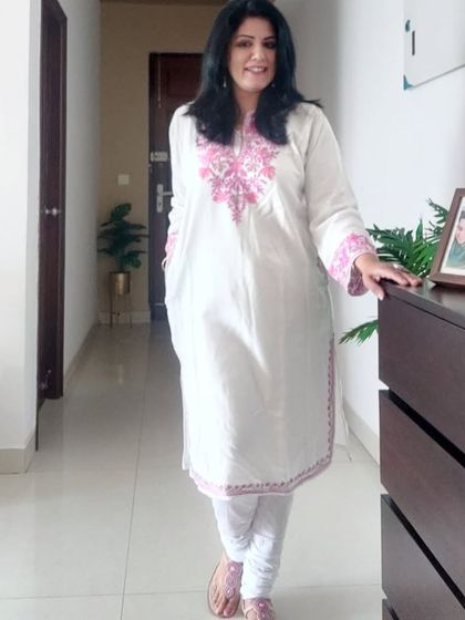 Another view of the white pheran, paired with white leggings and comfortable pink footwear.