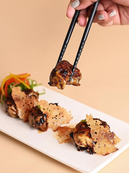 Our pan-fried chicken gyozas, tossed in a house-made chili bean jam. They are served with a delicate, crispy net for an extra layer of texture that makes them truly special.