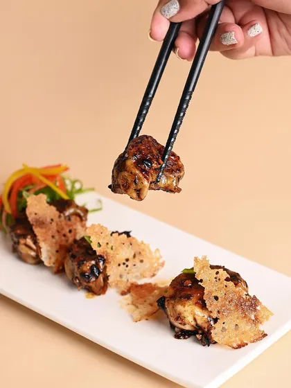 Our pan-fried chicken gyozas, tossed in a house-made chili bean jam. They are served with a delicate, crispy net for an extra layer of texture that makes them truly special.