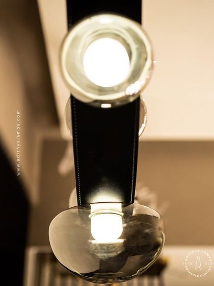 An unconventional design where smoked glass ovals are cradled by a flexible black leather strap. This fixture combines hard and soft textures for a uniquely modern and minimal aesthetic, perfect for creating a talking point in any room.