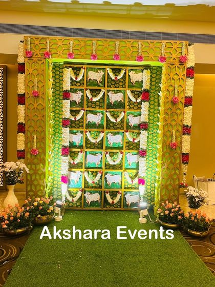A unique backdrop for a Seemantham ceremony, featuring panels with traditional cow motifs and floral garlands. The design is framed by gold lattice panels for an elegant touch.