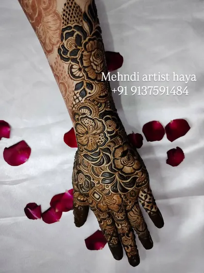 The contrast between the dark henna paste and the white background makes the intricate details of this floral and paisley design truly stand out.