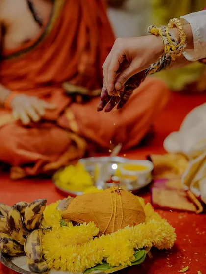 A detail shot of the sacred rituals, focusing on the hands performing the ceremony over a coconut and flowers. I ensure these symbolic moments are captured with reverence.