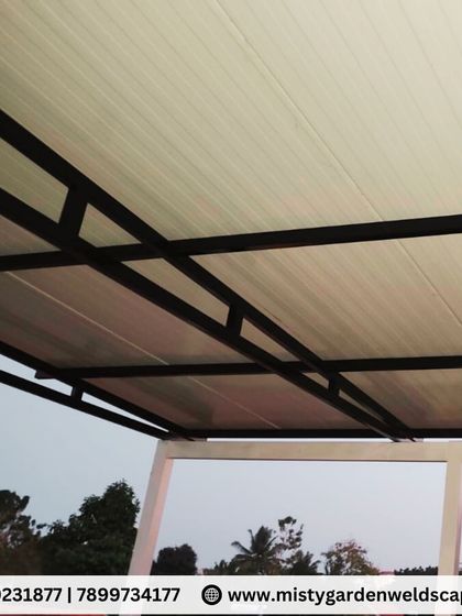 The underside of a puff sheet pergola at a villa in Whitefield. The clean white finish of the panels and the black metal frame create a modern and minimalist look.