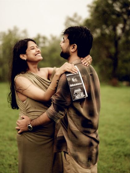 A joyful embrace, with the sonogram pictures playfully placed on his back. This photo is full of laughter and happiness, a perfect candid moment.