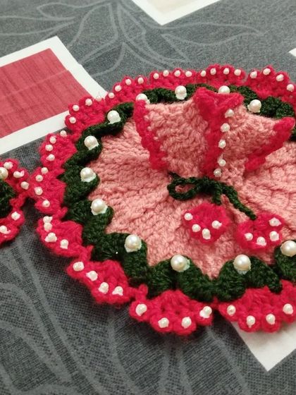 This complete set includes a pink and red floral poshak with a matching pearl-studded cap. The dress is designed to look like a blooming flower, perfect for your Bal Gopal.