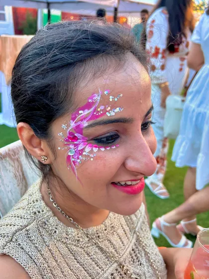 A delicate and dreamy floral design using shades of pink and white, accented with sparkling rhinestones. This is a perfect example of the kind of elegant face art you can offer for high-end parties and bridal events.
