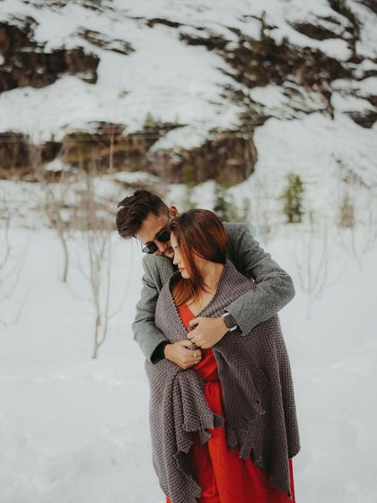 A caring gesture as the groom wraps his partner in a shawl to keep her warm during their snow shoot.