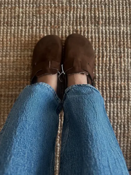 A customer trying on the clog-style Birken-inspired sandals in dark brown. They look great paired with casual blue jeans.
