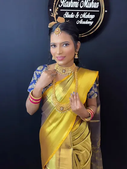 A beautiful portrait of a model styled as a South Indian bride, showcasing the classic combination of a silk saree and gold temple jewelry.