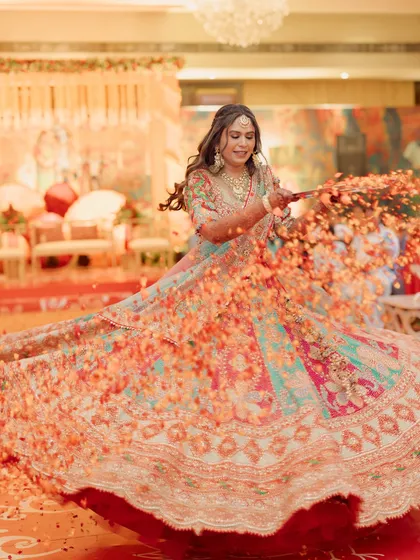 A stunning twirl by the bride during her Mehendi, with a shower of flower petals. This shot captures the color, movement, and joy of a daytime celebration.