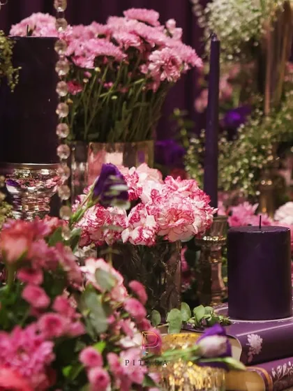 A beautiful vignette of pink carnations, baby's breath, and dark purple candles set atop vintage books. It's these small, curated moments that make a design feel complete.