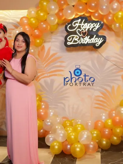 A lovely family portrait in front of a balloon arch and a light up number one sign at a first birthday party in a Delhi banquet hall.