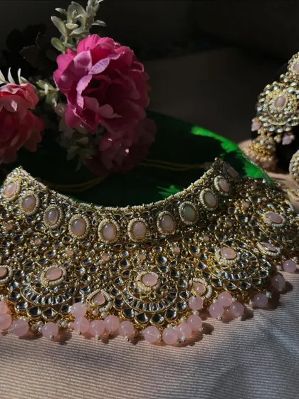 A full view of our pastel pink Kundan choker set against a dark background. The intricate details and the soft colour of the stones are clearly visible.