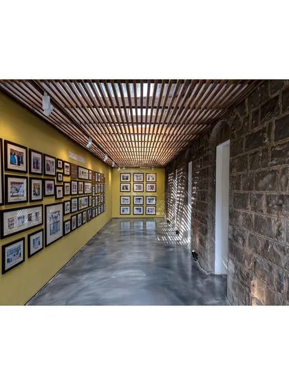 An exhibition gallery within the museum, where the original stone walls are left exposed. This design choice creates a textured backdrop for the historical photographs, grounding the narrative of the institution in the materiality of its origins.