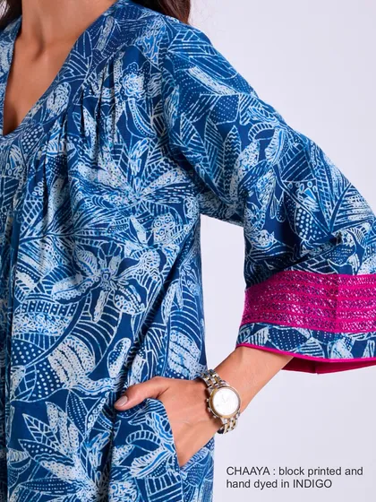 This detail shot of our Chaaya dress shows the practical side pocket and the flared sleeve with its pop of pink embroidery, blending functionality with beautiful design.