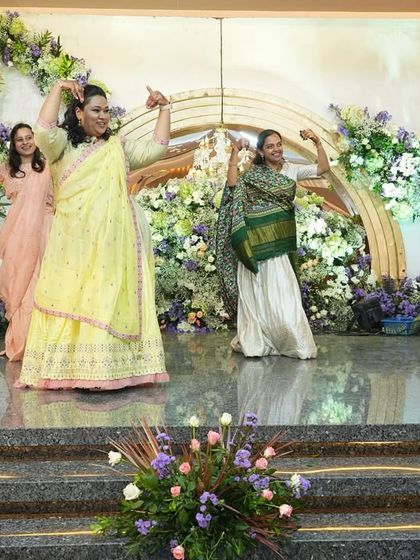 A group of ladies from the family performing a graceful and coordinated dance at an engagement. Their smiles show how much fun they're having.