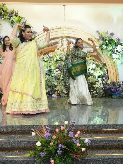 A group of ladies from the family performing a graceful and coordinated dance at an engagement. Their smiles show how much fun they're having.