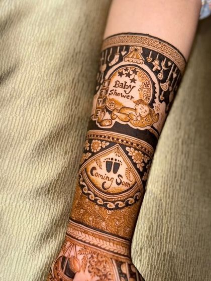 A detailed shot of the forearm, focusing on the "Baby Shower" and "Coming Soon" text and surrounding baby-themed motifs.