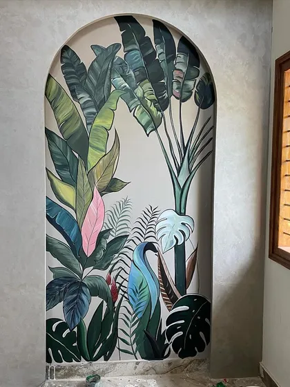We love bringing the outdoors in. This tropical mural, framed by a beautiful archway, adds a burst of life and color to a hallway, making it feel like a lush paradise. The variety of leaves, including a pop of pink, creates a vibrant, layered look.